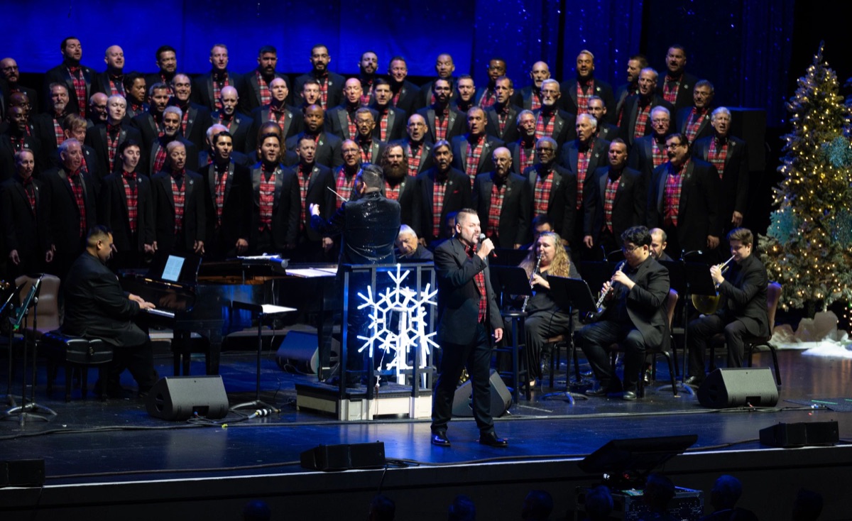 GMCSF chorus members singing in concert with vivid stage lighting.